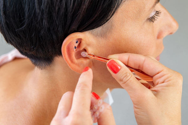 Ear seeds being applied to woman's ear