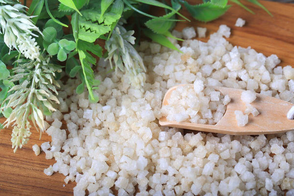 Epsom salt with green herbs on a wooden surface