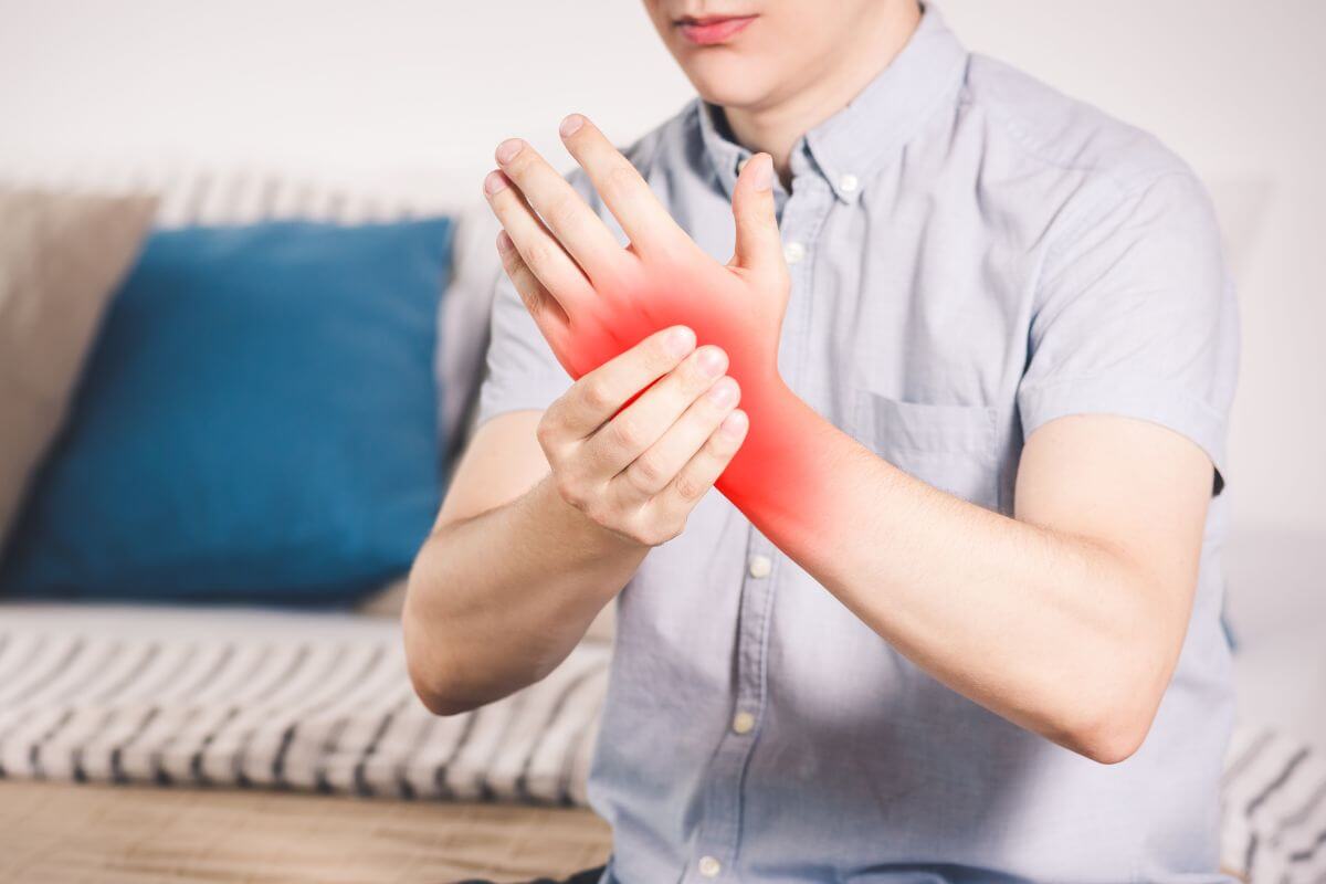 A person holding their painful wrist due to a hand cramp