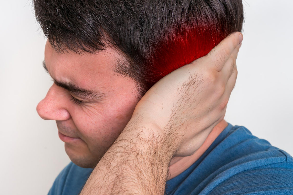 Man holding the base of his skull with red highlight indicating pain area, illustrating neck/head tension